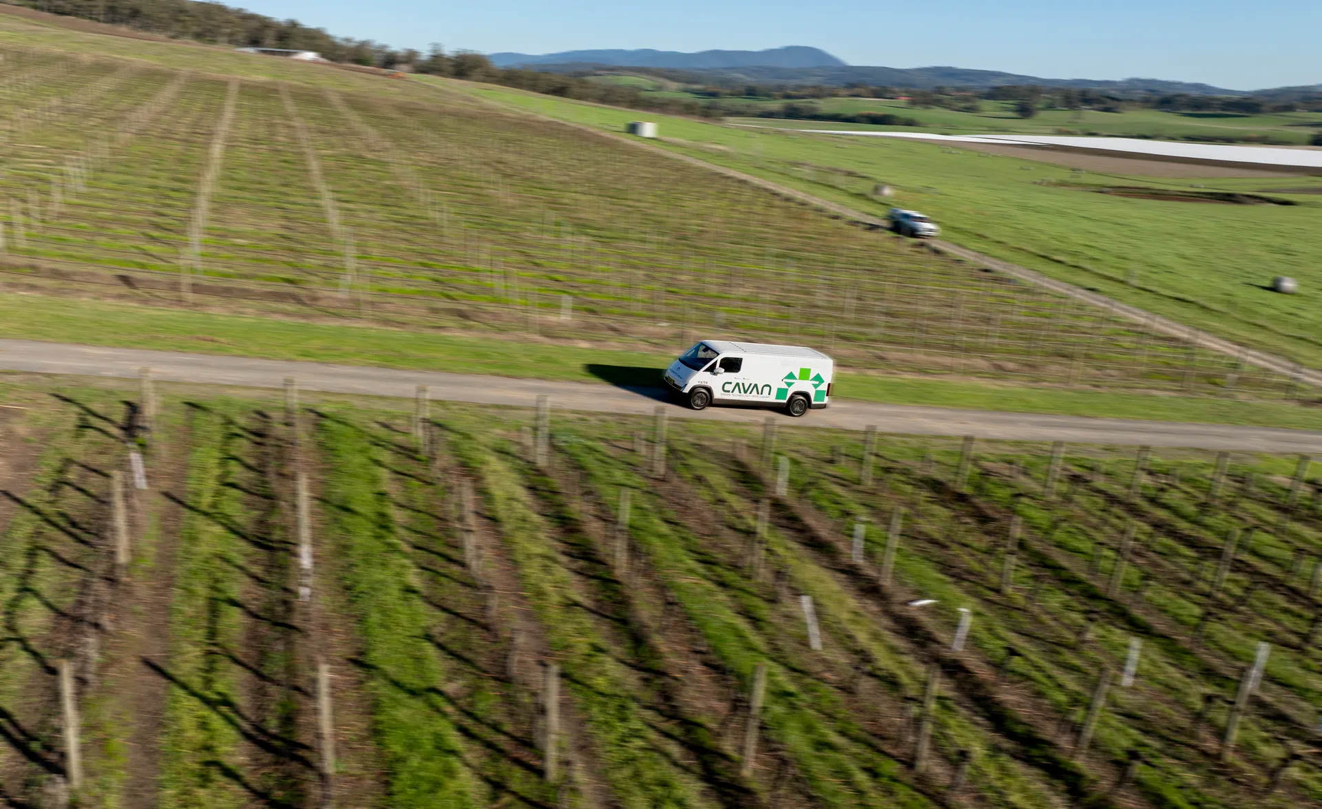 Aerial view of a Cavan electric van on a gravel road between young vineyard blocks