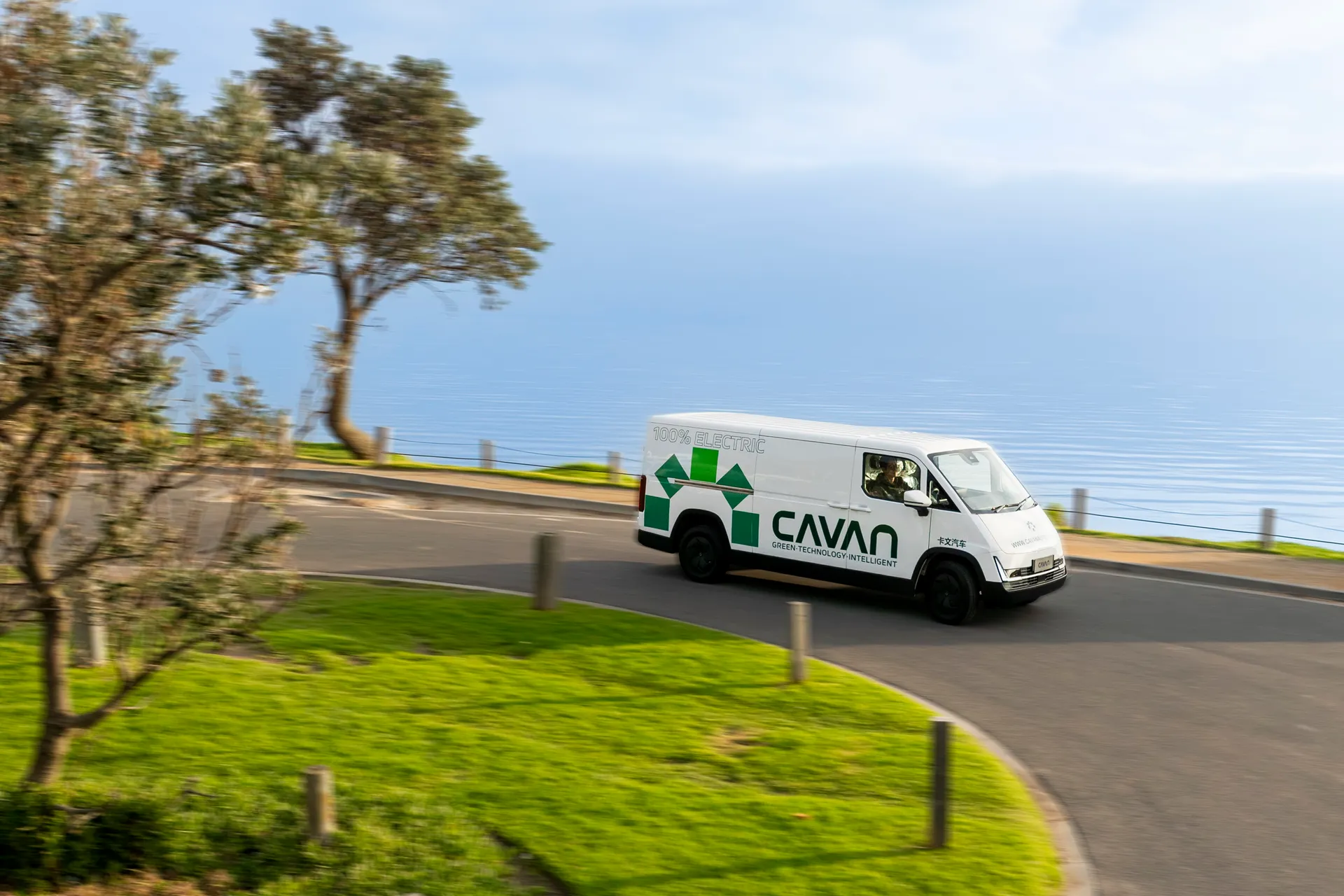 A Cavan electric van cornering on a coastal road with the sea beyond